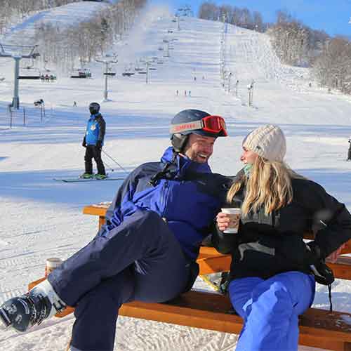 couple enjoying a beverage at base of slopes
