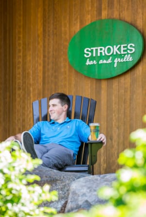 Golfer relaxes outside Strokes Bar and Grille
